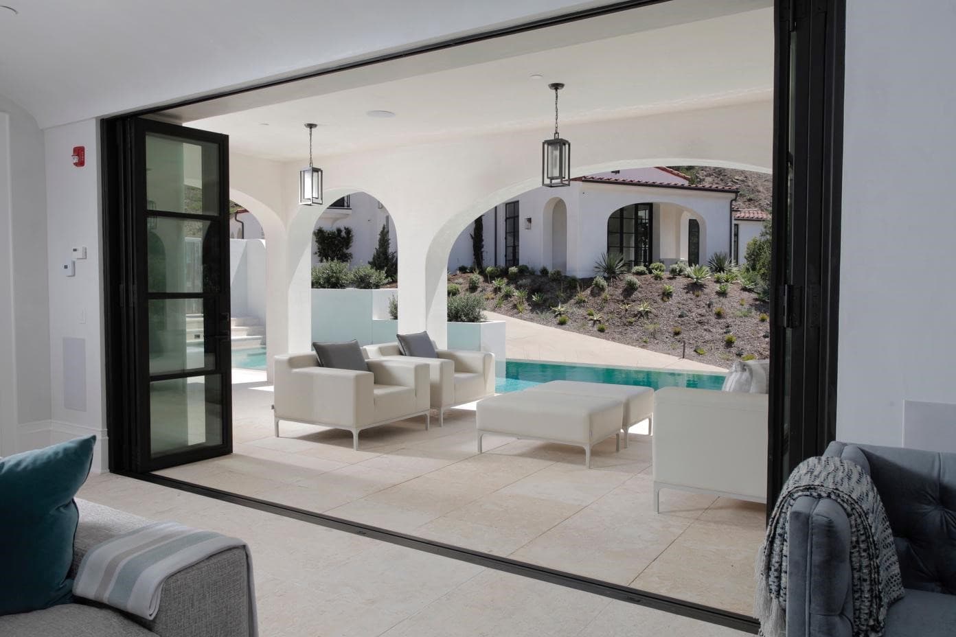 Great room with steel-framed doors folded open to a covered terrace